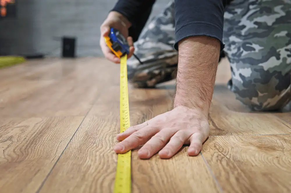 Homem medindo com um trena o comprimento da área para colocar piso