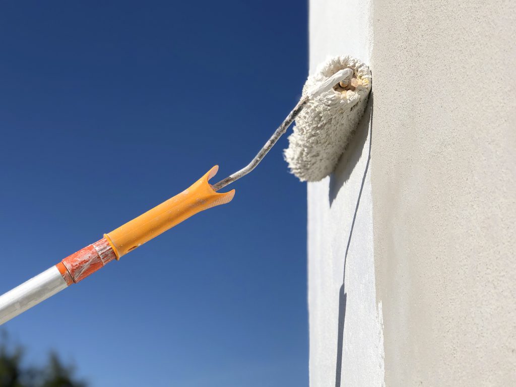 Um rolo de pintura passando em uma parede rebocada