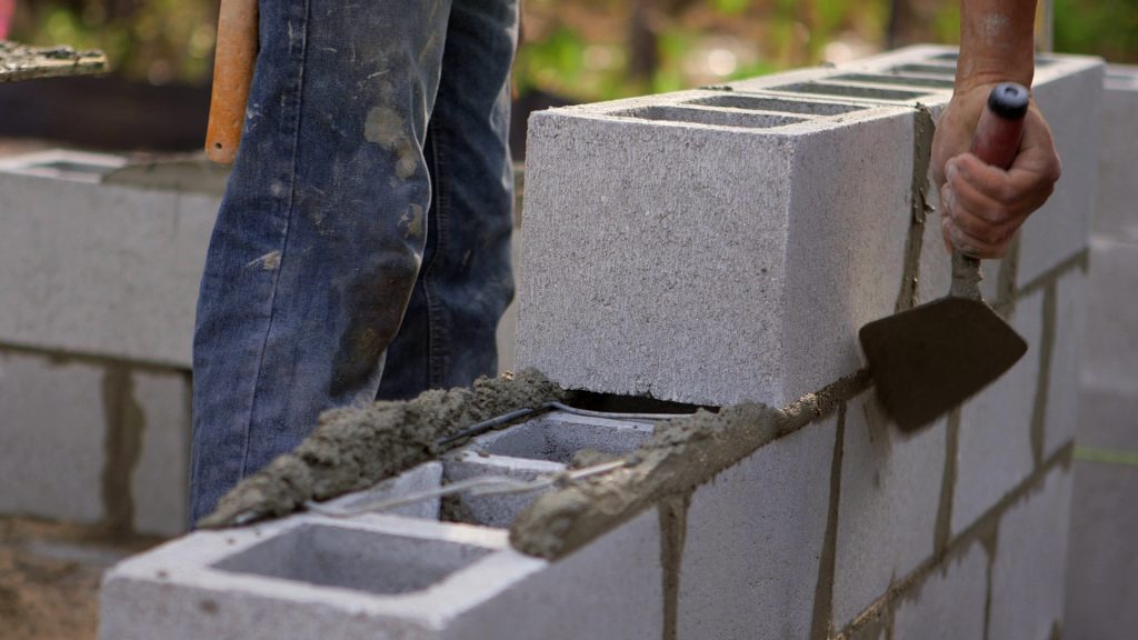 Homem construindo uma parede com blocos de concreto