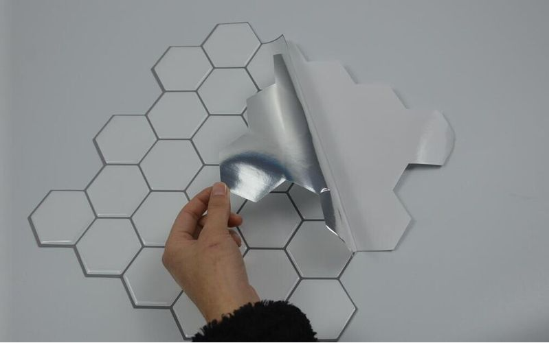 Pastilha adesiva retangular sendo aplicas em uma parede branca