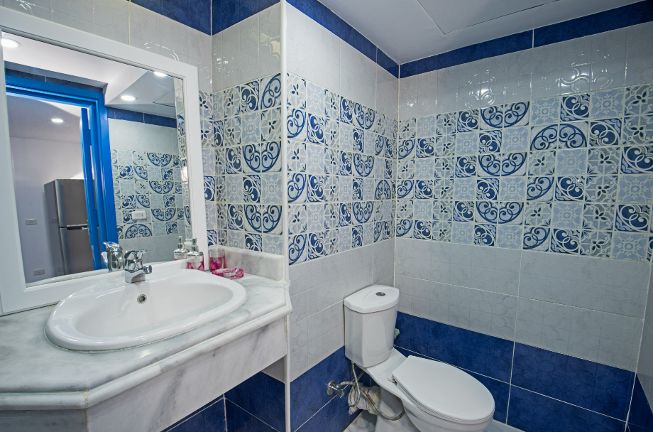 Banheiro com revestimento em ladrilho hidráulico branco com detalhes em azul
