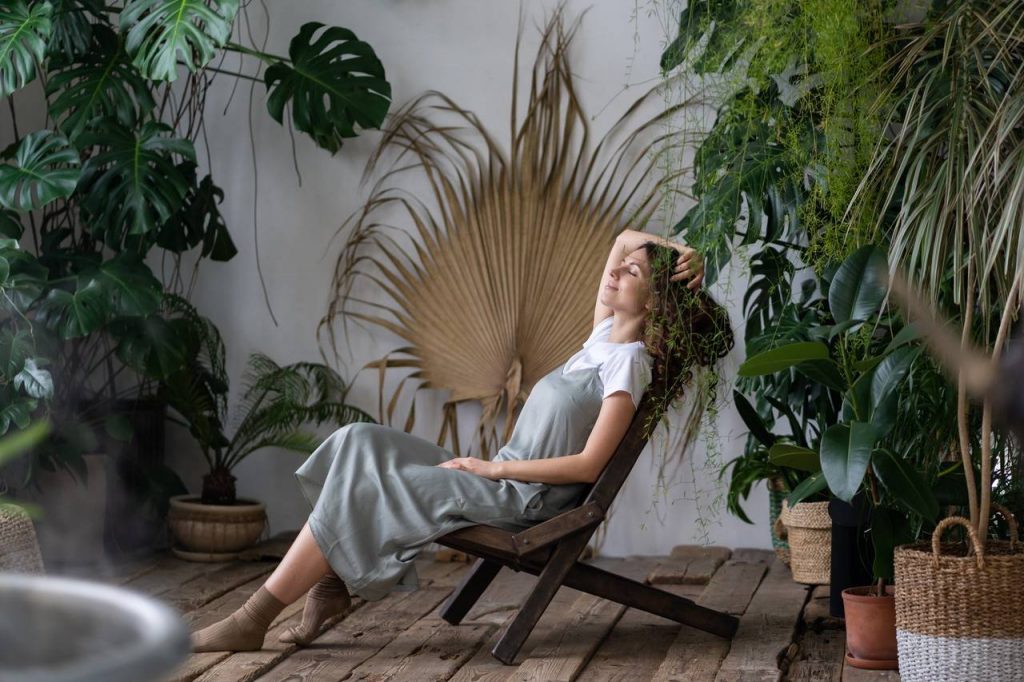 mulher relaxando em um ambiente decorado por plantas diversas