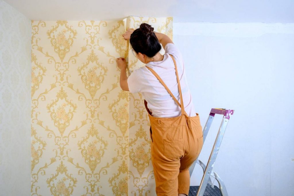 Mulher refinando os acabamentos após a aplicação do papel de parede