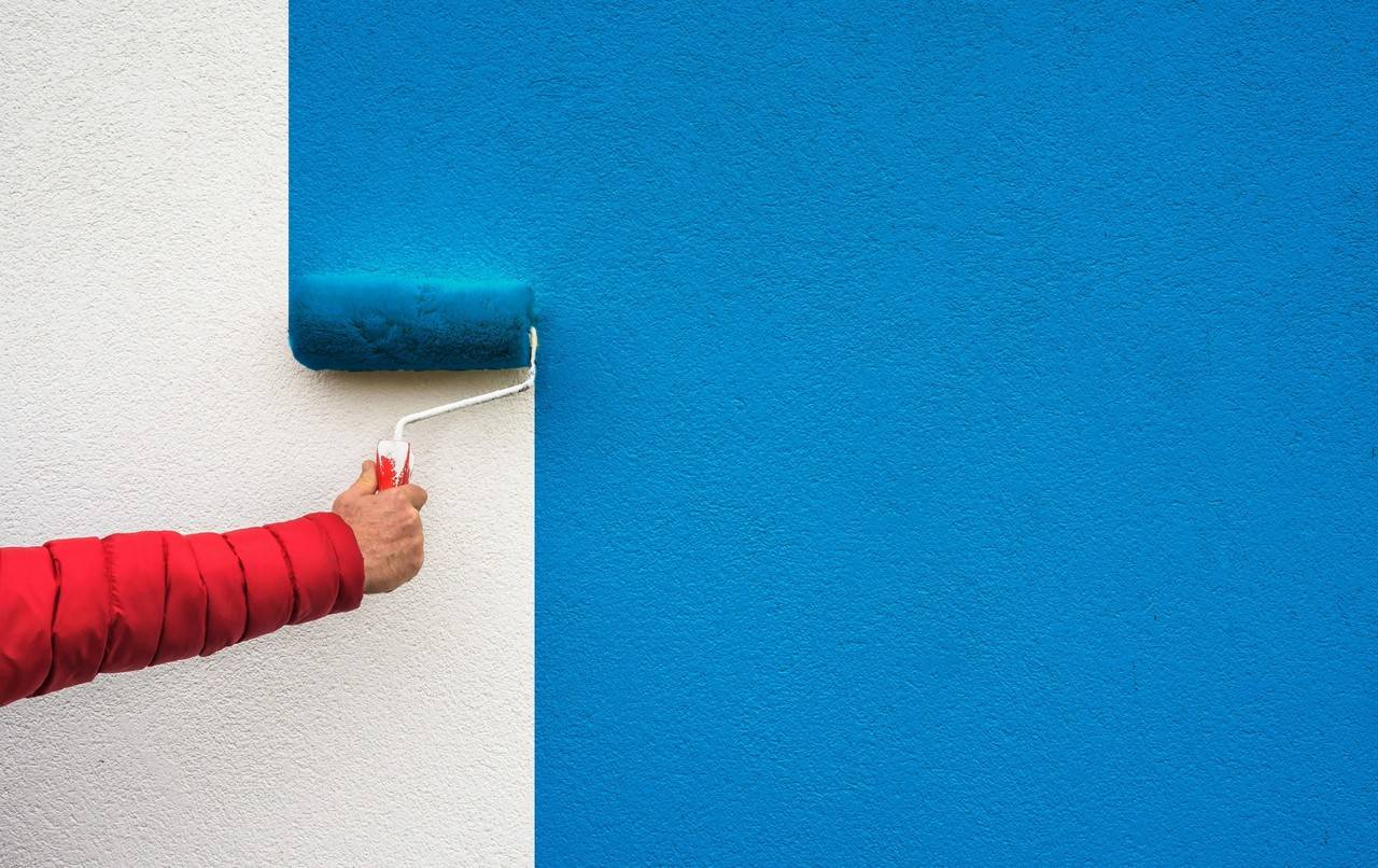 Homem pintando uma parede de azul