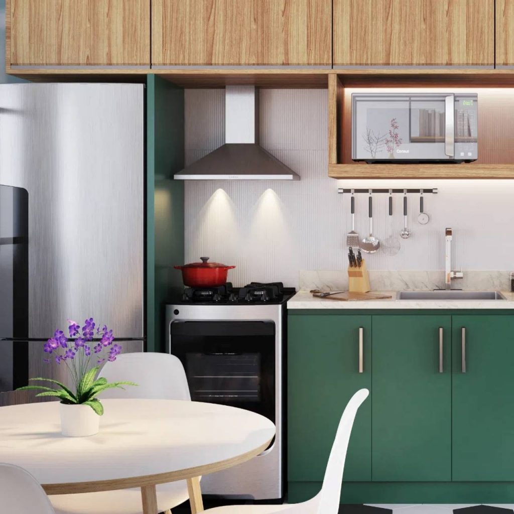 Cozinha planejada com tons de verde e amadeirado com eletrodomésticos como micro-ondas e geladeira, fogão e coifa