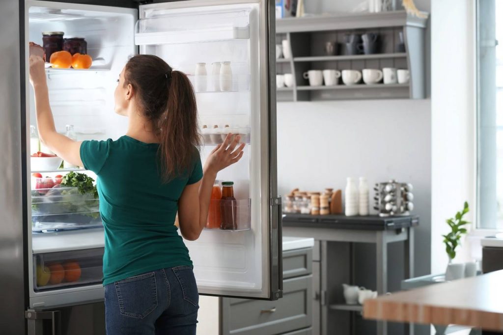 Mulher abrindo a porta da geladeira