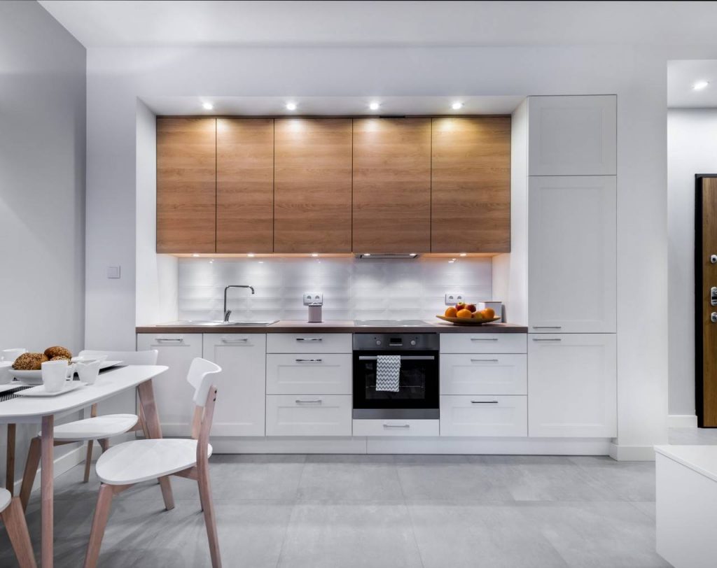 Cozinha planejada na cor branca e madeira com iluminação em destaque no móvel
