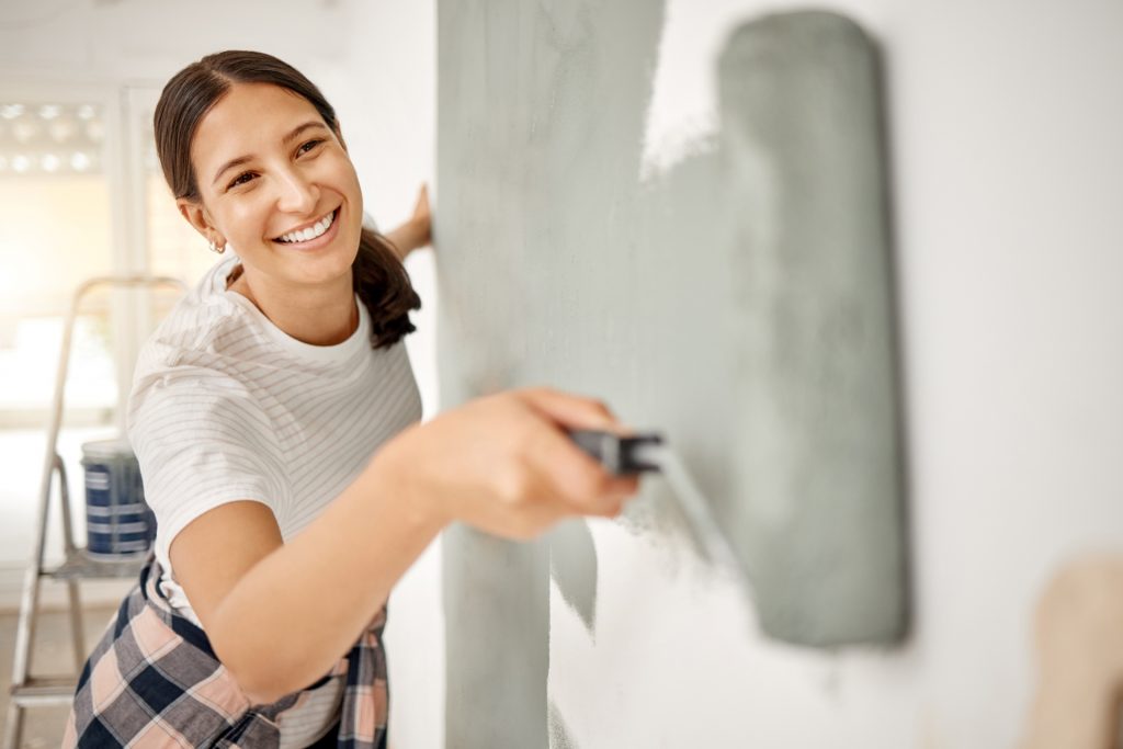 mulher pintando uma parede de cinza para valorizar o imóvel para alugar