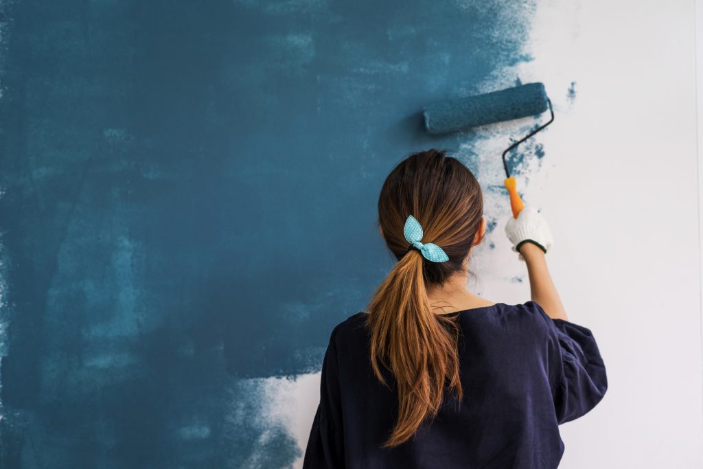 mulher pintando a parede com um rolo, acessórios para pintura de parede