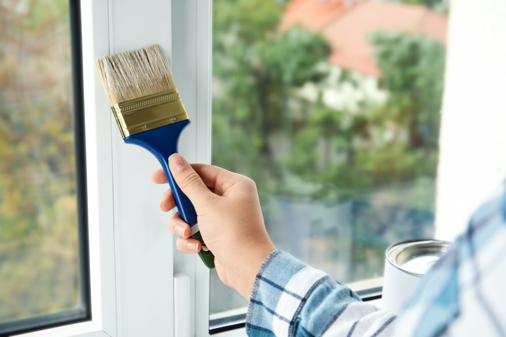 mulher deslizando o pincel na abertura de janela preparando a superfície para a pintura