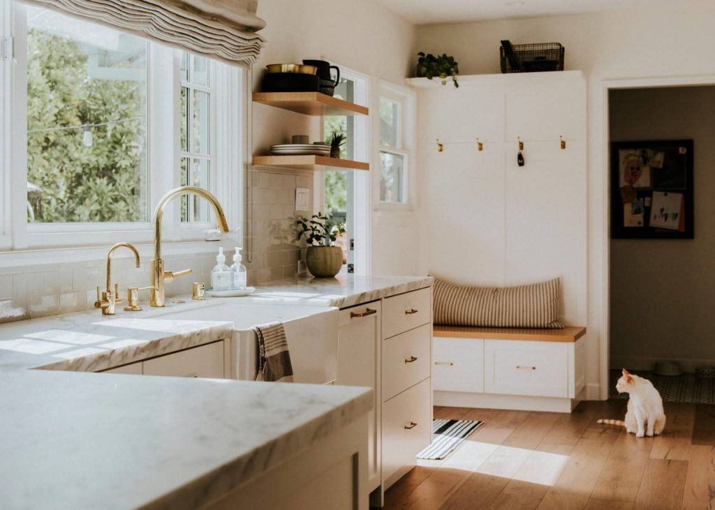 Imagem de uma cozinha com móveis brancos e detalhes dourados