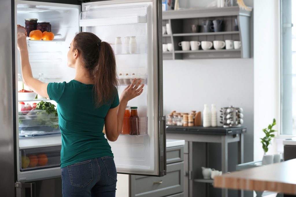 mulher pegando alimento da geladeira