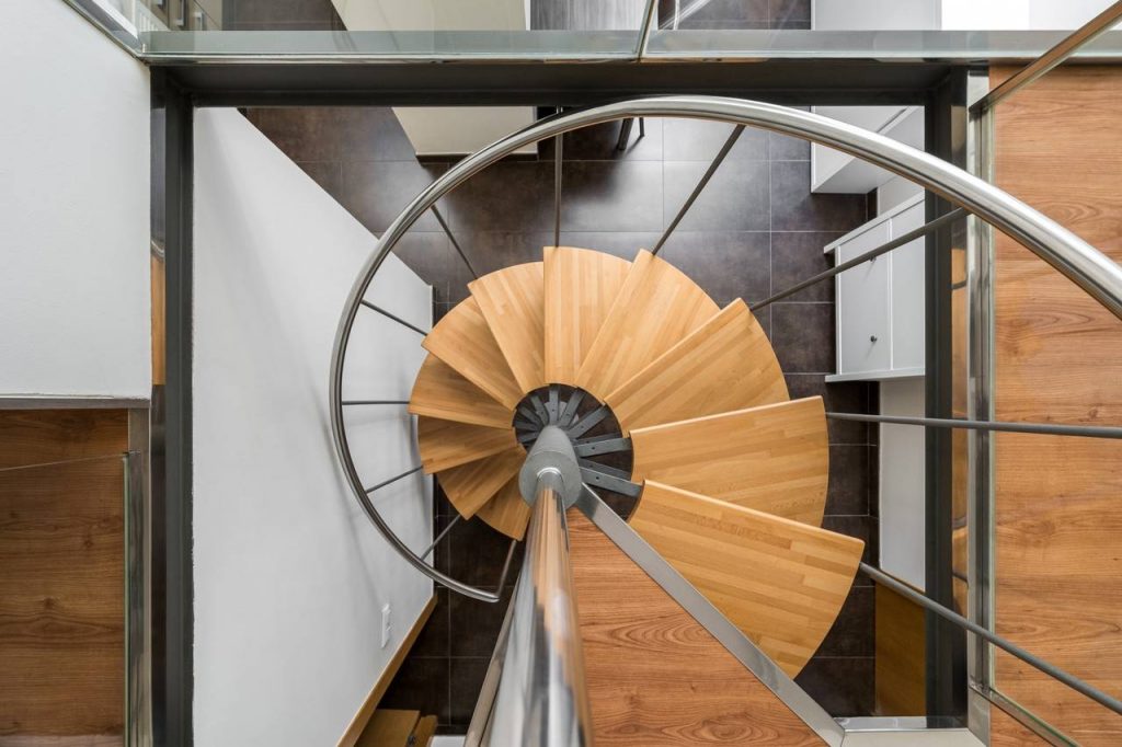 Escada em forma de caracol com degraus em madeira e corrimão em metal é um dos tipos de escadas