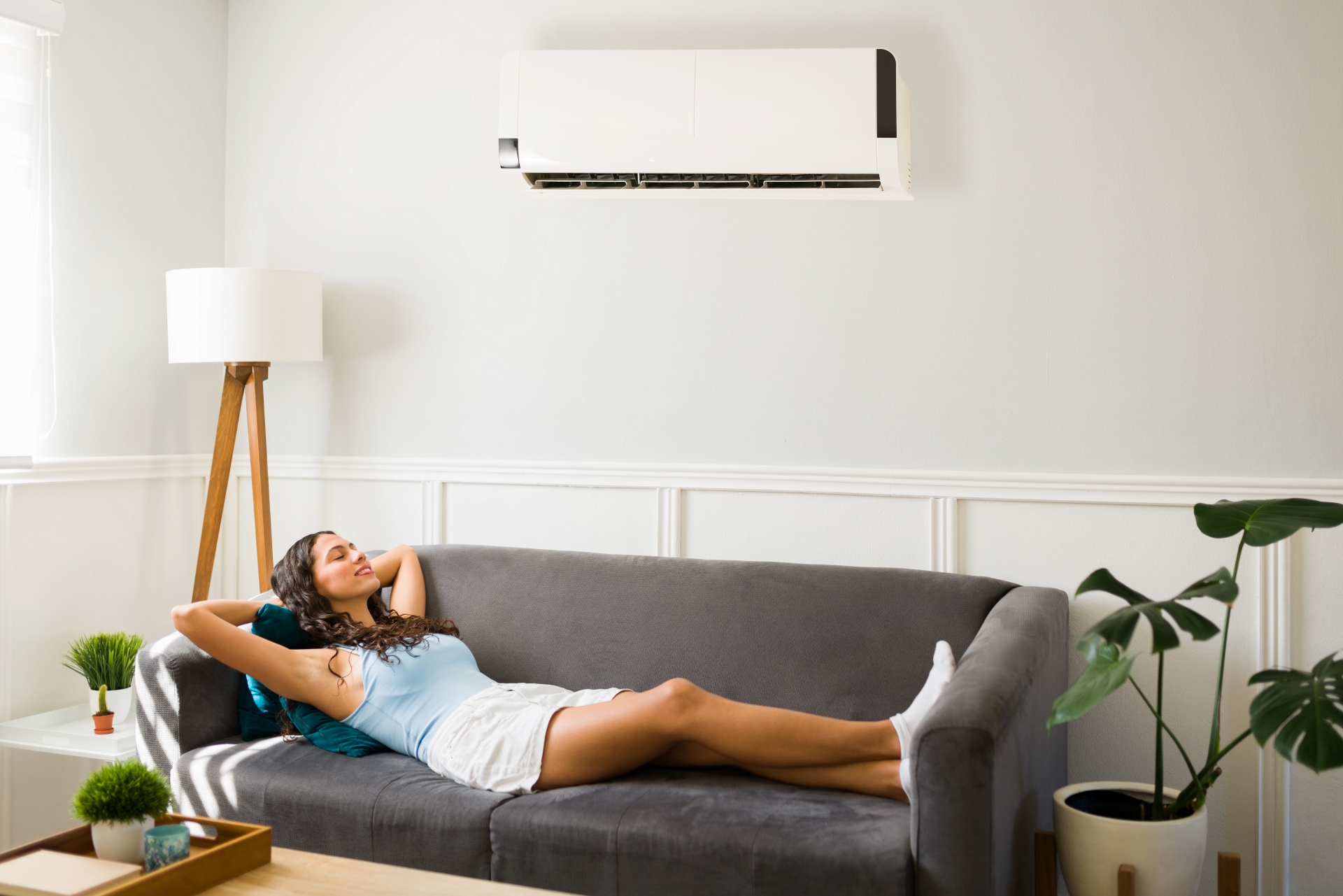 mulher deitada no sofá da sala relaxando com um ar-condicionado no verão
