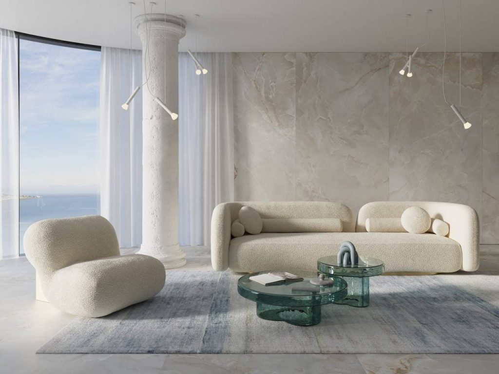 Revestimento de parede marmorizado em sala, com sofás no tom branco e mesa de centro em vidro