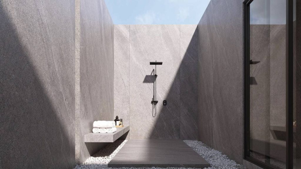 Revestimento de parede para ambiente externo em pedras, ducha externa e prateleira suspensa com toalhas brancas