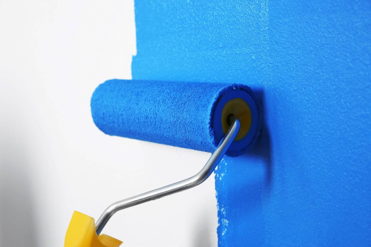 Detalhe de rolo de espuma pintando parede na cor azul