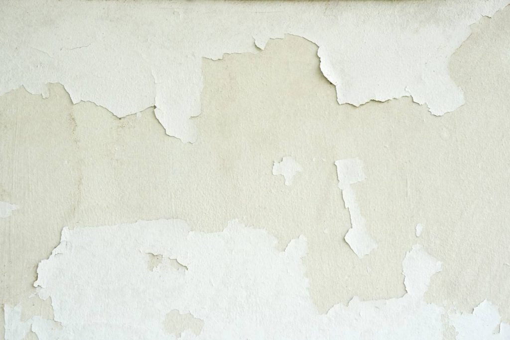 detalhe de parede com pintura descascada no tom branco e bege