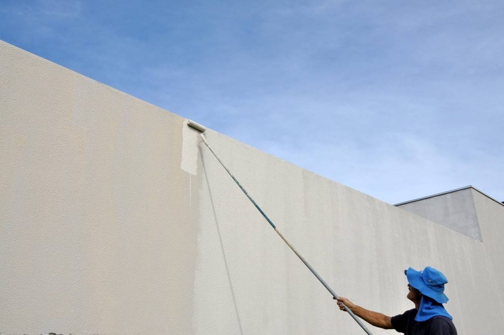 Homem pintando parede com rolo de espuma