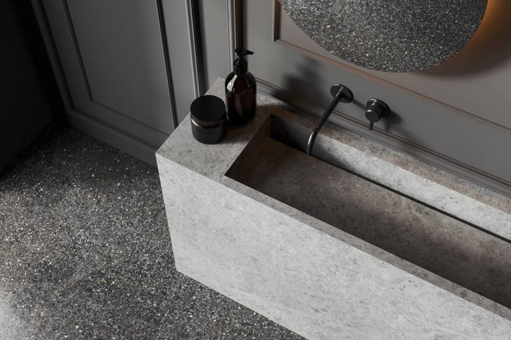 piso granilite aplicado em lavabo, com pia esculpida e torneira de parede no tom preto