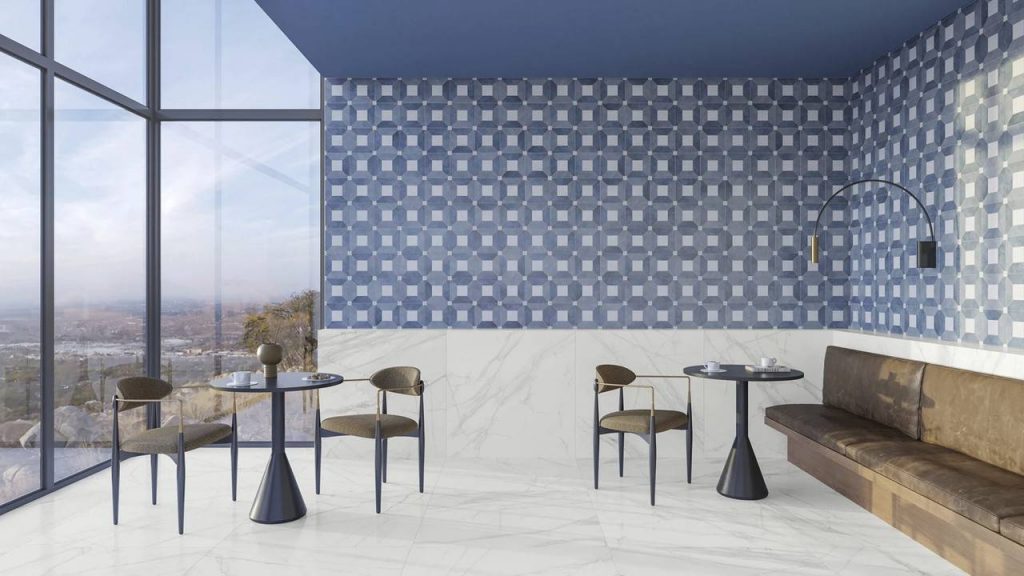 Revestimento de parede em porcelanato decorado no tom azul e branco, parte parede em vidro, duas mesas redondas com cadeiras e sofá