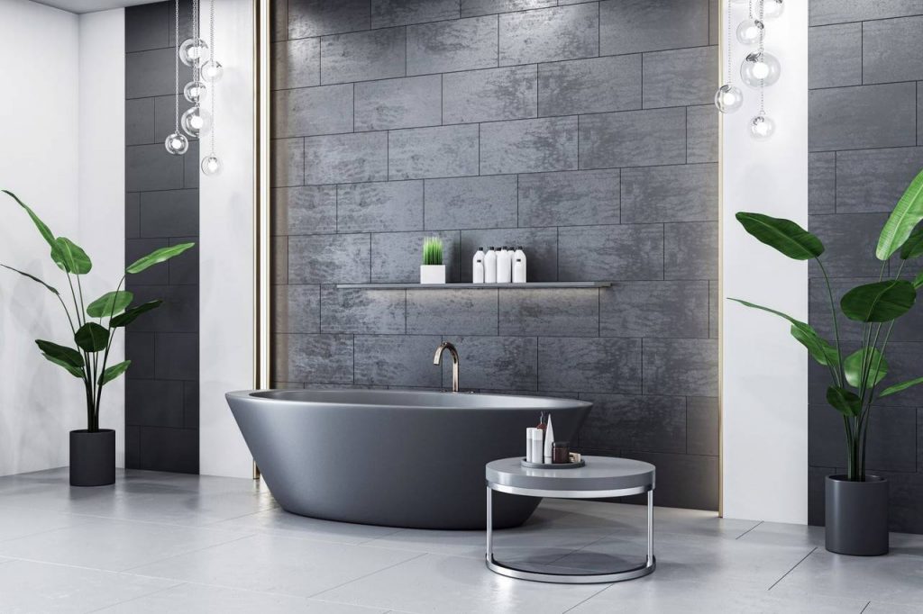 Detalhe de parede de banheiro com porcelanato no tom preto, banheira e mesa de canto, vasos de plantas de cor predominante escura