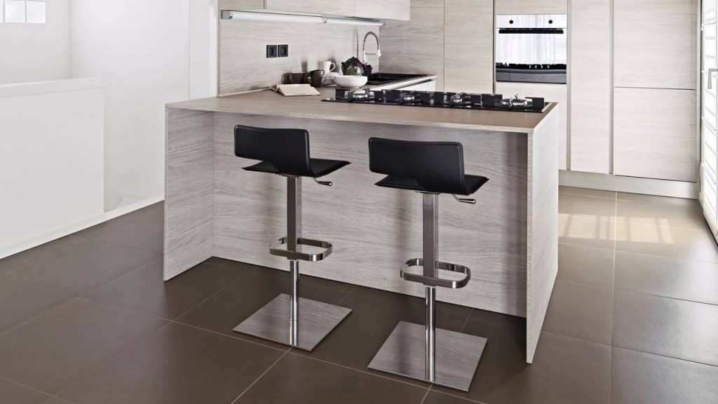 Cozinha com bancada e móveis planejados em MDF, duas cadeiras, cooktop