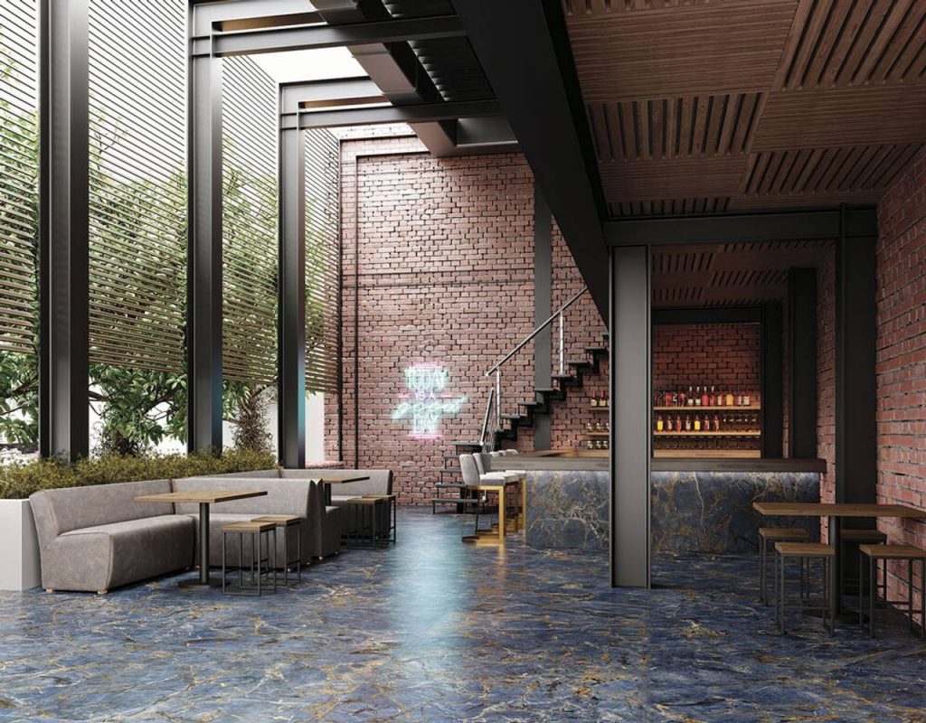 Mezanino de conceito aberto com sofás, mesas, balcão e prateleira de bebidas, com pisos Málaga, está entre as marcas exclusivas Cassol