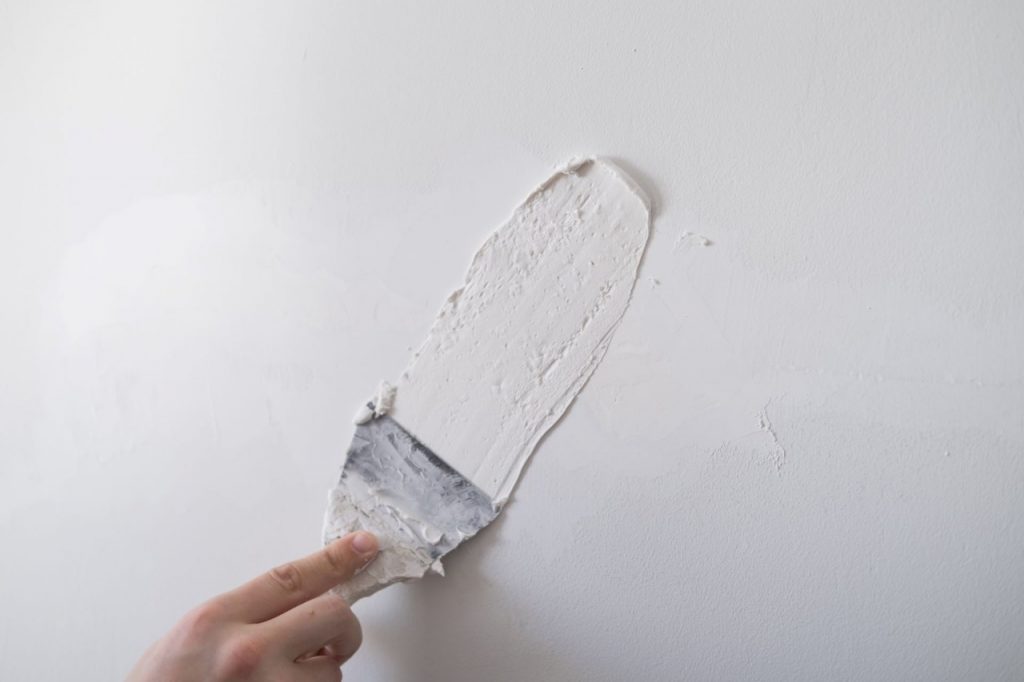 Pintor utilizando espátula para fazer textura em parede da cor branco, é um dos tipos de textura para paredes