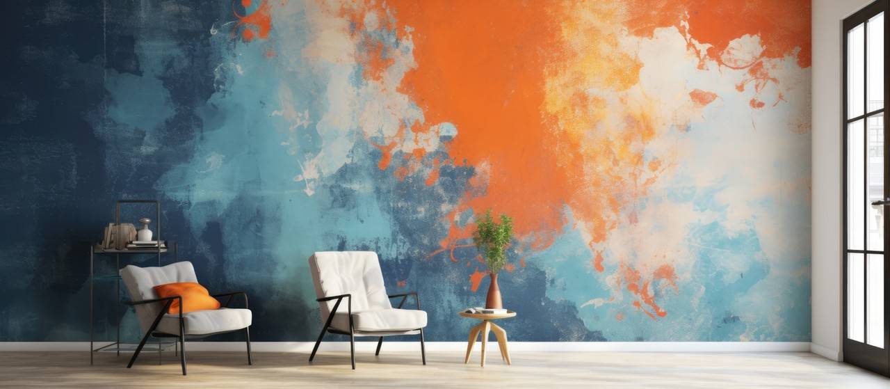 Parede decorada com pintura em textura trabalhada nas cores laranjada e azul, duas poltronas e uma mesa de canto