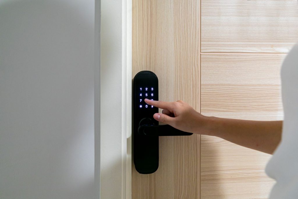 mulher digitando a senha numa fechadura eletrônica para abrir a porta de uma casa inteligente
