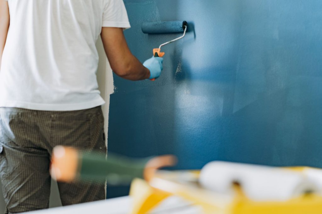 homem pintando a parede de azul com tinta comprada na liquidação na cassol centerlar