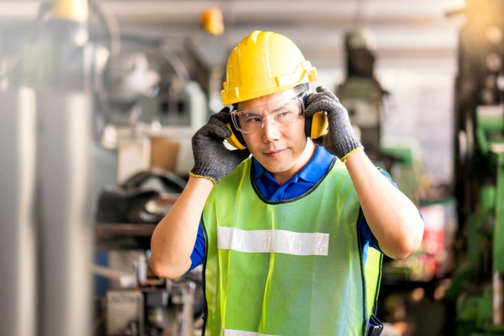 Trabalhador com capacete amarelo, óculos de proteção e colete